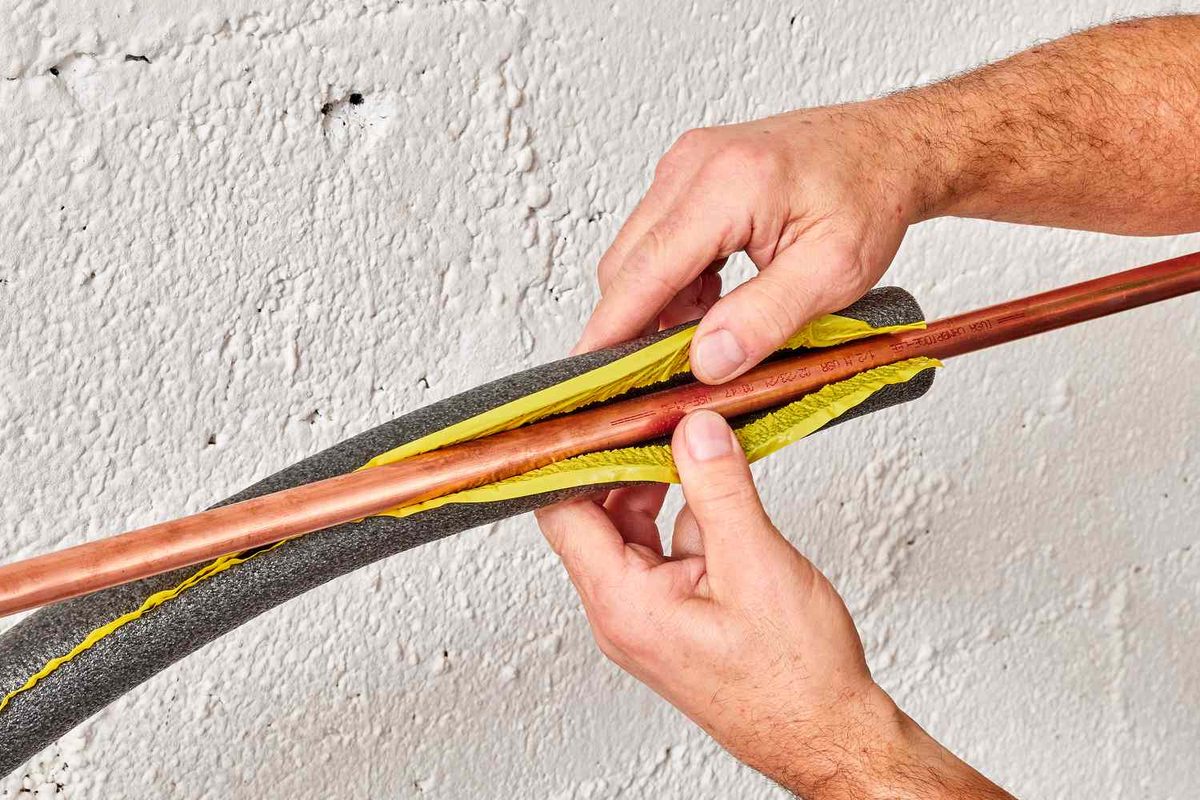 Insulating an exposed pipe before a freeze Foam insulation sleeve being fitted over a copper water pipe